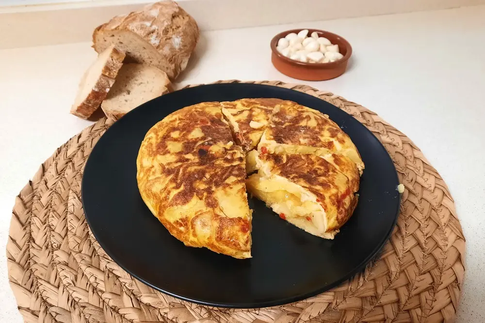 Tortilla de patata con ajos en aceite y pimientos del piquillo